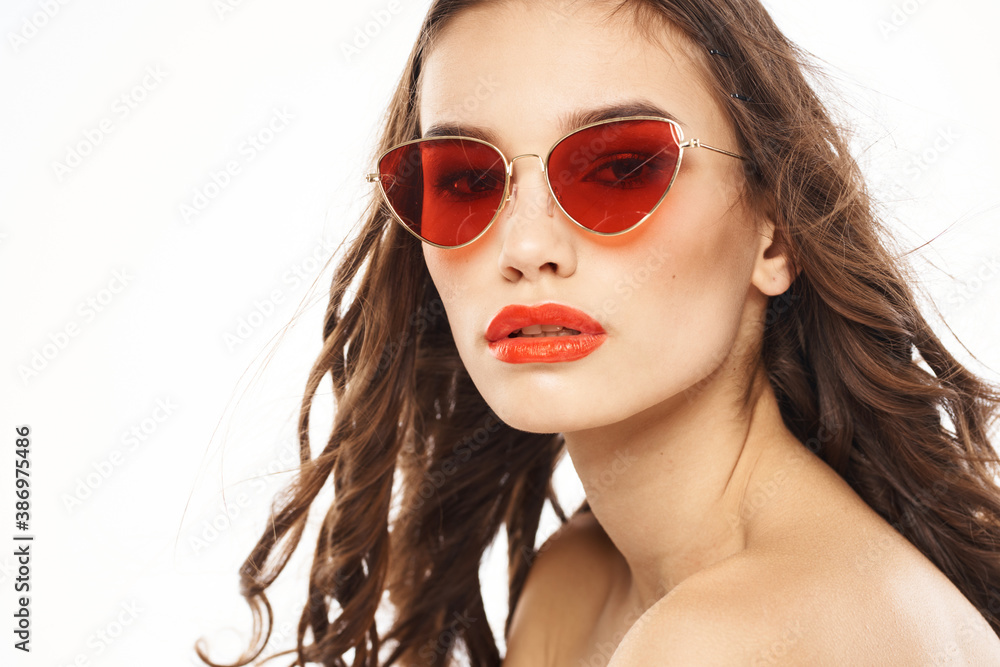 Portrait of brunette woman in sunglasses naked shoulders light background Portrait of brunette woman in sunglasses naked shoulders light background