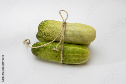 Raw green cucumbers bounding with rope on white background photo