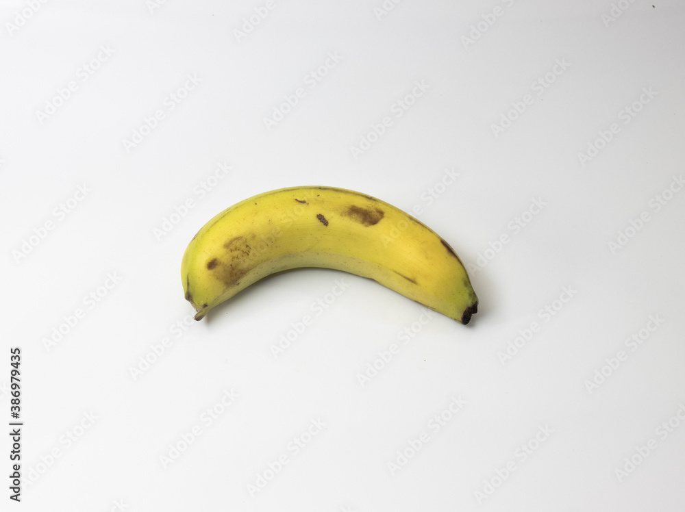Single isolated yellow green rip banana on white background