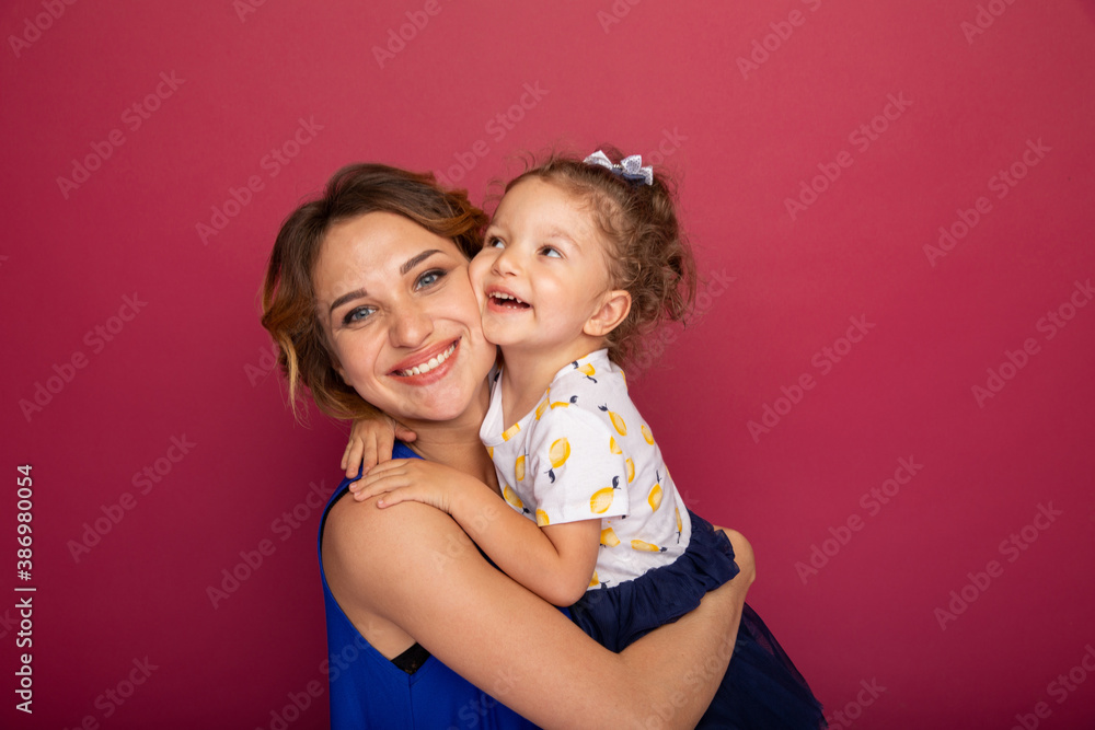 Mother holding little daughter on the hands and smiling standing in a bright studio Mother holding little daughter on the hands and smiling standing in a bright studio