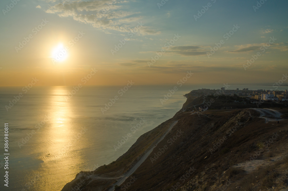 Sunset over the sea, near a steep slope