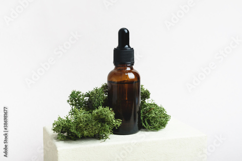 Fototapeta Naklejka Na Ścianę i Meble -  Brown serum glass bottle with pipette with the green moss. Natural Organic Spa Cosmetic concept. Front view.