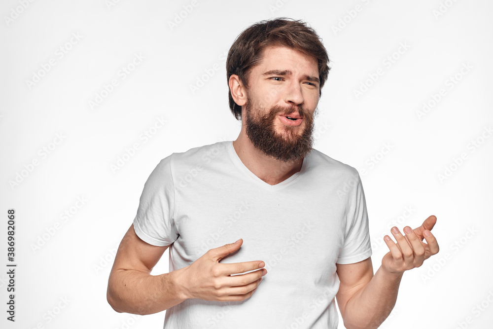 cheerful bearded man in a white t-shirt emotions gestures with his hands light background studio cheerful bearded man in a white t-shirt emotions gestures with his hands light background studio