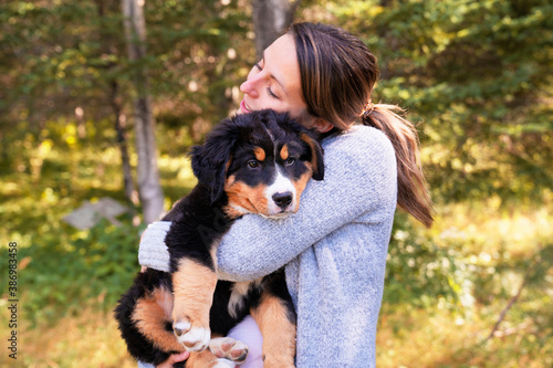 Bernese Mountain Dog puppy with his owner standing in forest park