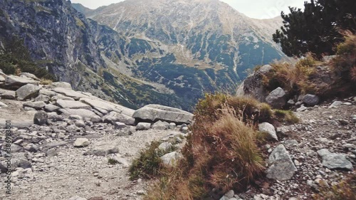 Camera flying over the edge of cliff to the mountain lake view, Stabilized Shot, 4K, POV. Epic Steadicam footage of stormy nature in rocky cloudy mountains. Misty Mountains Series.  photo