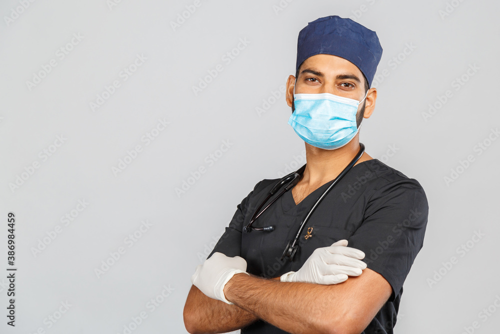 indian doctor or surgeon in black uniform with stethoscope and white latex gloves, blue medical mask on gray background indian doctor or surgeon in black uniform with stethoscope and white latex gloves, blue medical mask on gray background