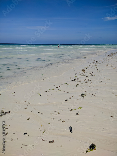 Zanzibar, Tanzania - December 10, 2019: Low tide on the ocean Zanzibar. On the shore lies seaweed. Vertical.