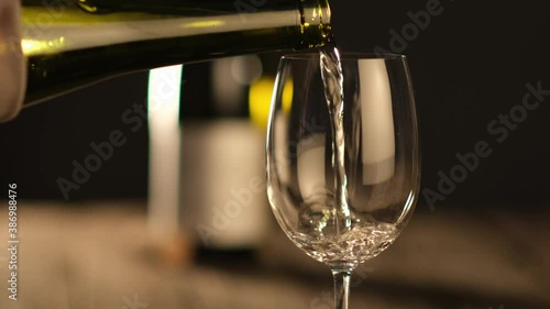 waiter pouring white wine in a glass on a wooden restaurant table
