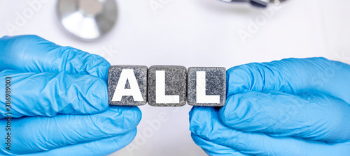 ALL Acute lymphoblastic leukemia - word from stone blocks with letters holding by a doctor's hands in medical protective gloves