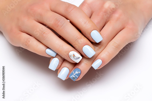 White  light blue  manicure with the moon  with stones  crystals  rhinestones dots on short square nails close-up on a white background.