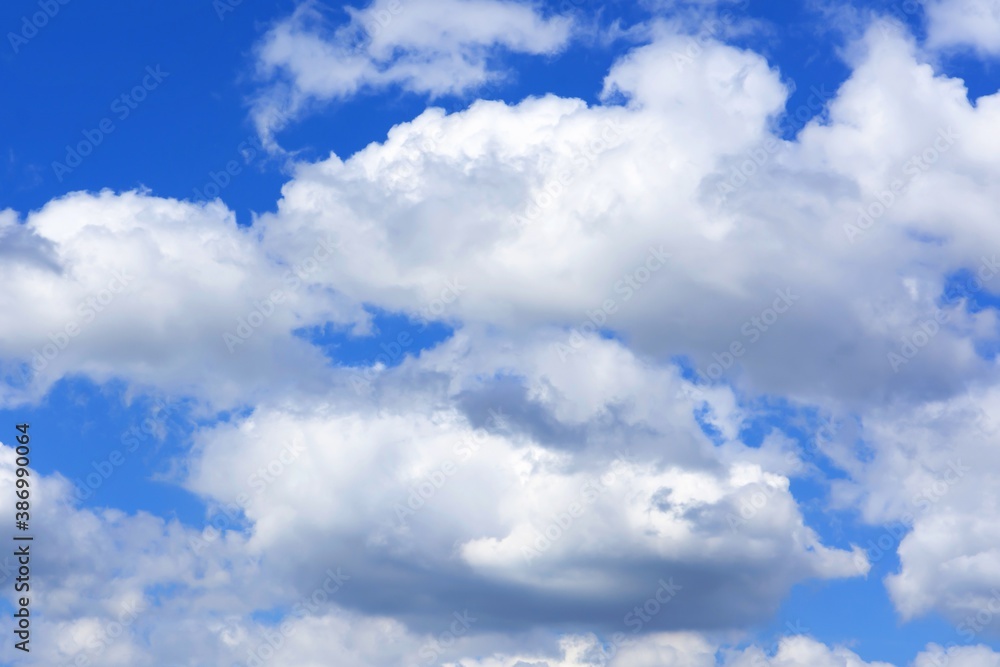 Naklejka premium white cumulus clouds against a bright blue sky
