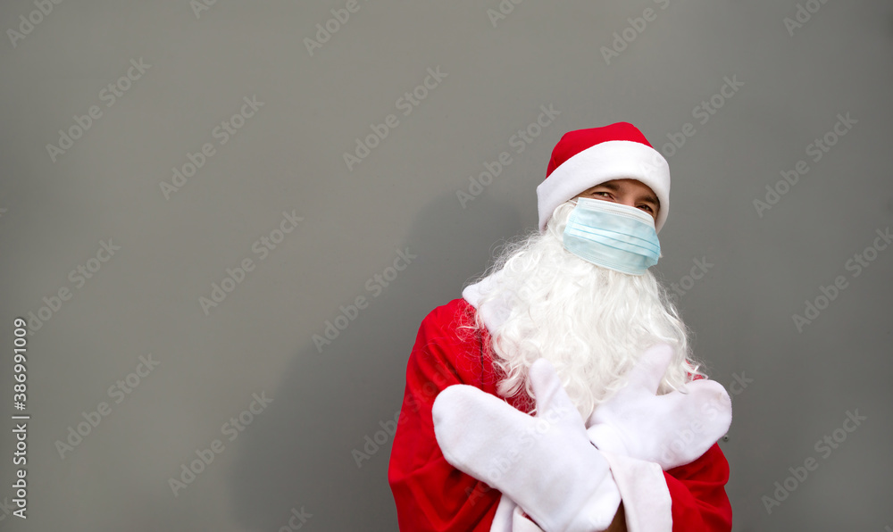 Santa Claus with white beard in red coat in a medical mask. Christmas in the coronavirus pandemic, seasonal diseases, SARS and pneumonia in the holidays. Protection from viruses in the new year. Gray Santa Claus with white beard in red coat in a medical mask. Christmas in the coronavirus pandemic, seasonal diseases, SARS and pneumonia in the holidays. Protection from viruses in the new year. Gray