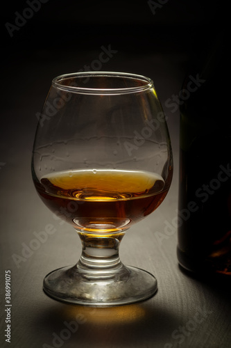 Bottle and glass of brandy on a wooden background.