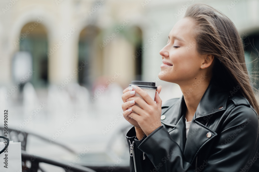 portrait of a Thrifty confident brunette woman of European appearance holding a coffee Cup to take away in a cafe. I bought things clothes for myself and my family, there are bags nearby portrait of a Thrifty confident brunette woman of European appearance holding a coffee Cup to take away in a cafe. I bought things clothes for myself and my family, there are bags nearby