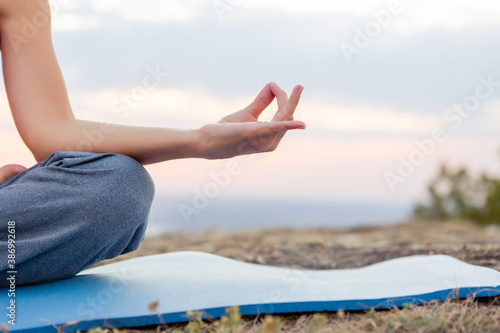 young pregnant woman does yoga outdoors. Yoga at sunset