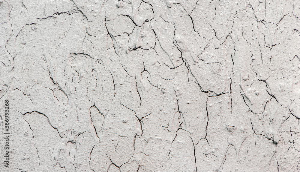 Fototapeta premium Heavily cracked stucco wall texture, macro shot. Grainy and fractured surface. Old wall background.