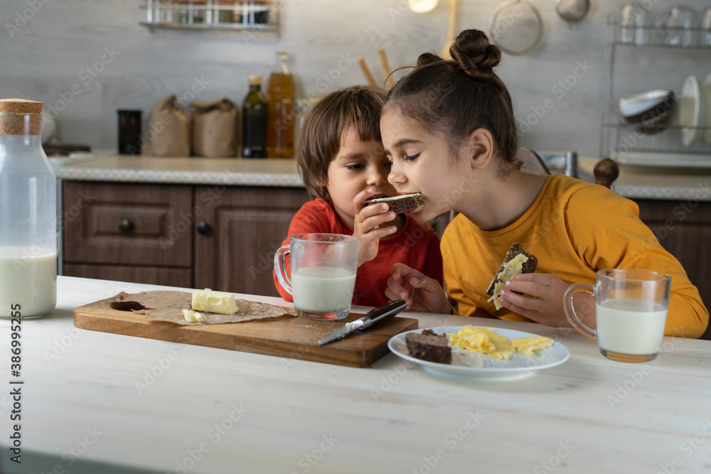 Children spread chocolate paste on toast bread in the kitchen background. Breakfast happy family having fun with food Children spread chocolate paste on toast bread in the kitchen background. Breakfast happy family having fun with food