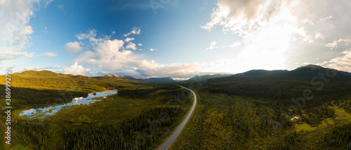 Beautiful Panoramic View of Scenic Road surrounded by Forest, Lake and Mountains at Sunset. Aerial Drone Shot in Canadian Nature. Taken by Alaska Highway, Southern Yukon, Canada.