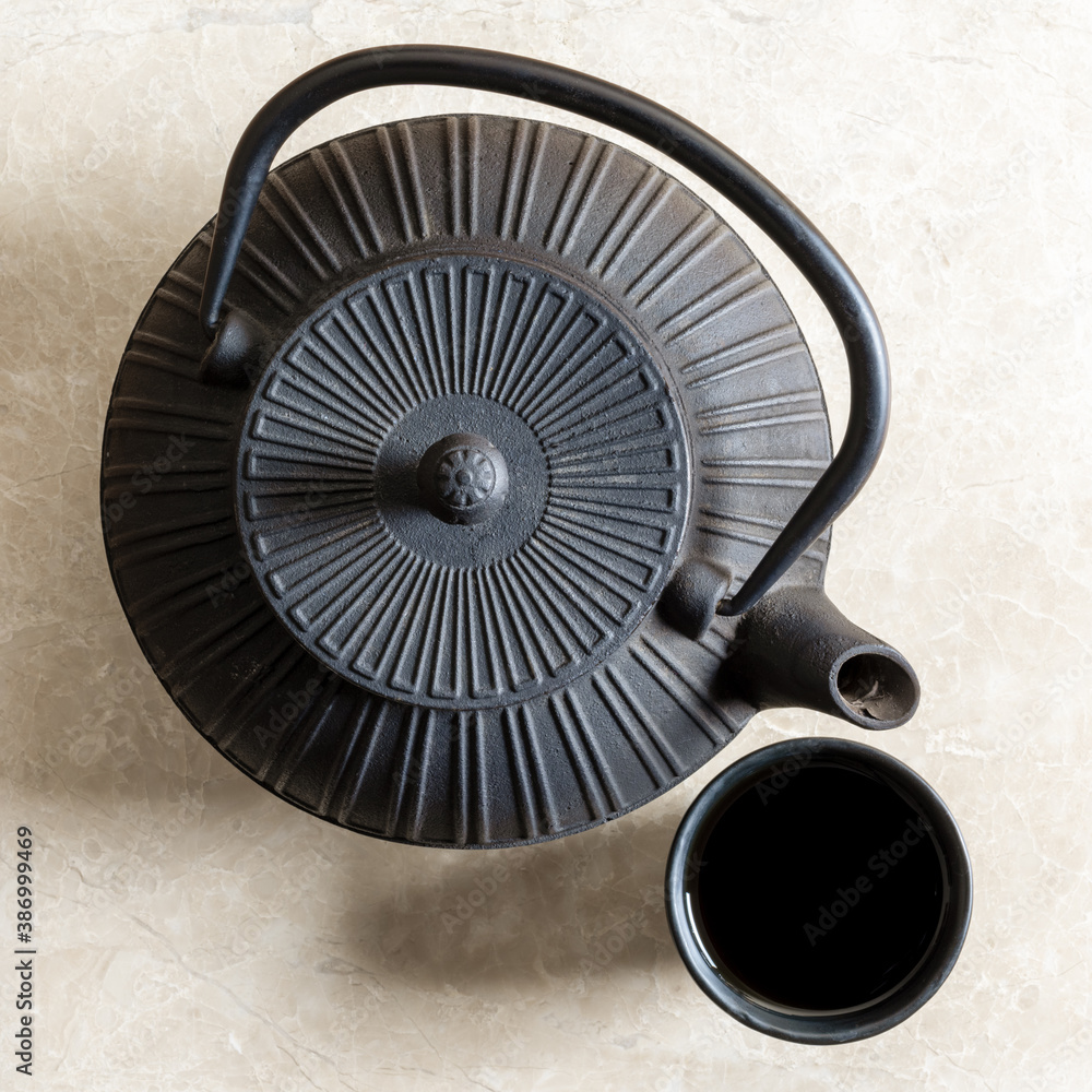 Top view of iron cast teapot and traditional clay tea cup filled with black tea - obrazy, fototapety, plakaty 