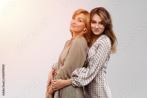 Happy beautiful women: mother and adult daughter closeup portrait isolated on white background