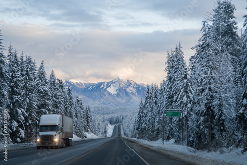 Truck driving through the rocky mountains in winter on the Trans Canada Highway in British Columbia near Rogers pass with good road conditions snowy winter mountain landscape scenery as backdrop