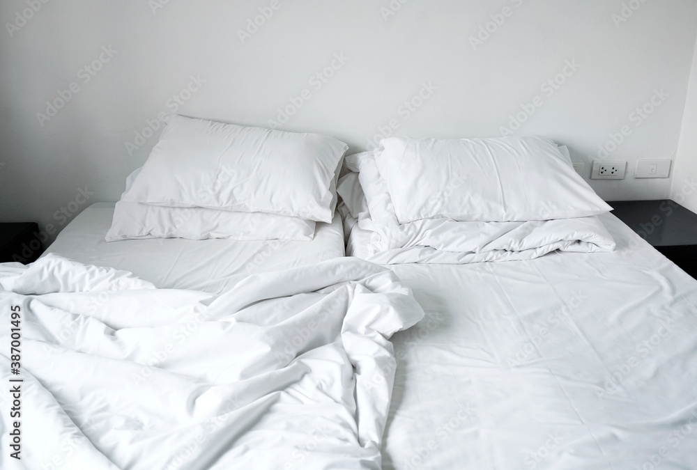 Messy and unmade double beds white pillow and blanket on bedroom hotel, Interior white room in cloudy day Messy and unmade double beds white pillow and blanket on bedroom hotel, Interior white room in cloudy day