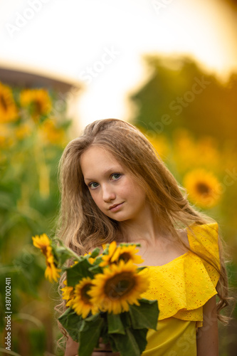 Cute teenage girl in yellow dress on the field with sunflowers