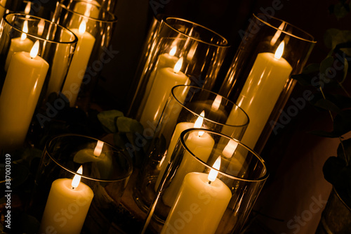 Romantic wedding display of wax candles glowing with small flames in glass vases centrepieces photo