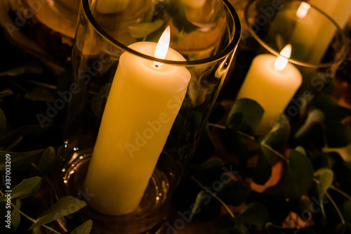 Romantic wedding display of wax candles glowing with small flames in glass vases centrepieces photo