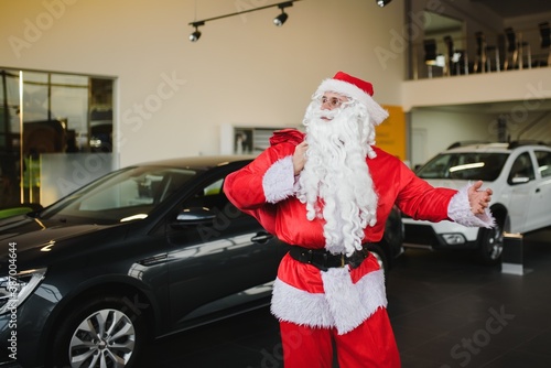 Santa Claus near a new car in a car dealership.