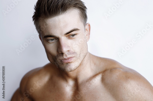 Muscular sexy model sports young man on white background. Portrait of beautiful smiling healthy guy.