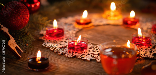 Winter ornamental decoration with burning candles on wooden rustic table. Mulled wine punch with gingerbread in foreground. Christmas holidays and New Year theme. Close-up