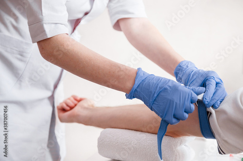 Nurse fastens the medical tourniquet on arm before taking blood test photo