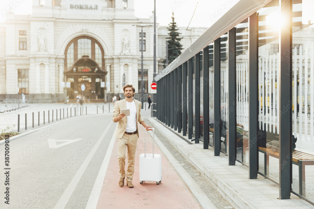 Businessman walking on street with suitcase and tablet Businessman walking on street with suitcase and tablet