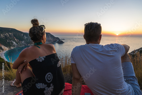 Young couple waiting for sun to set at beach Petani, Kefalonia