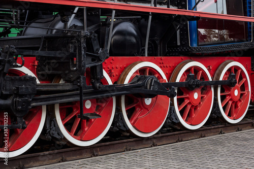 Old black and red retro steam locomotive wheels at the railway station. Vintage train staying on the railroad.