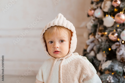 Toddler boy in a handmade jumpsuit. baby near the Christmas tree for Christmas