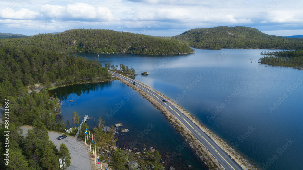 Aerial view of the road near the lake and the forest from above. Vacations, eco tourism, nature of Scandinavia.
