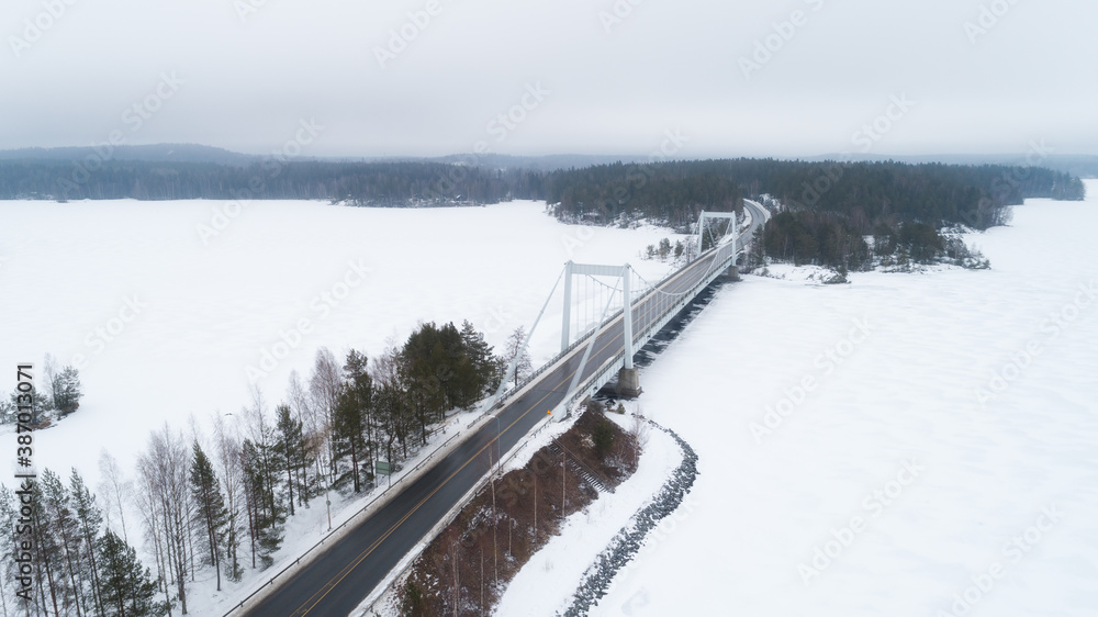 Aerial top view of bridge road above frozen lake in snow winter Finland.