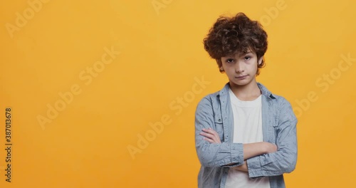 Portrait of little boy with folded arms expressing contempt or annoyance, looking at camera with condemnation
