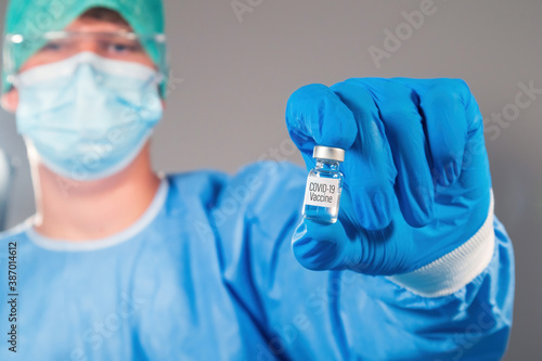 Virologist doctor with coronavirus vaccine in a medical vial. Close up