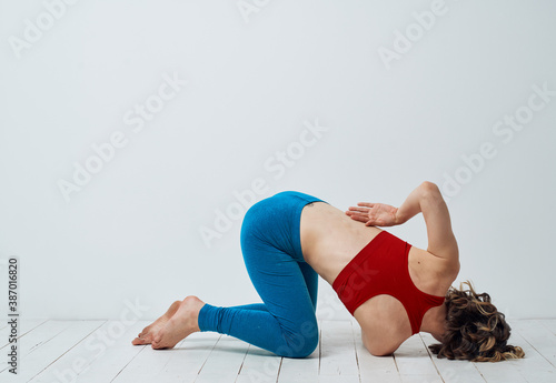 A woman is kneeling on the floor with her arm bent and yoga asana exercises