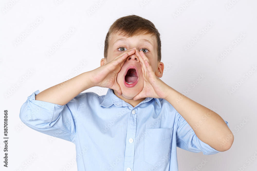 The boy expresses emotions, shouts, pressing his hands to his mouth. Isolated over white background. The boy expresses emotions, shouts, pressing his hands to his mouth. Isolated over white background.