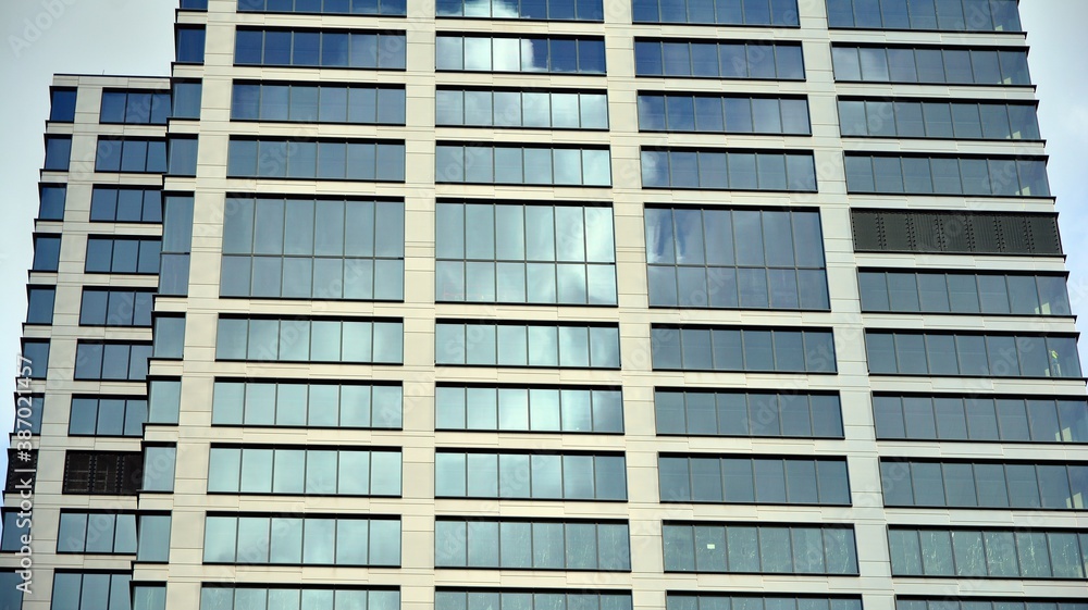 Blue curtain wall made of toned glass and steel constructions under blue sky. A fragment of a building. Blue curtain wall made of toned glass and steel constructions under blue sky. A fragment of a building.