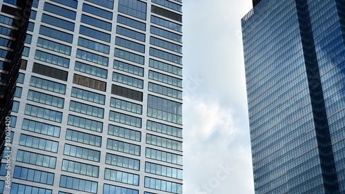 Blue curtain wall made of toned glass and steel constructions under blue sky. A fragment of a building.