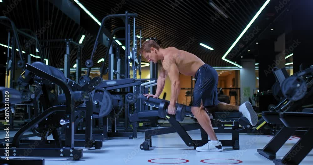 Male athlete does a dumbbell row with an emphasis on a bench, basic exercises for the muscles of the arms. Athlete shakes the broadest muscles of the back and biceps, a gym with modern equipment. 4k Male athlete does a dumbbell row with an emphasis on a bench, basic exercises for the muscles of the arms. Athlete shakes the broadest muscles of the back and biceps, a gym with modern equipment. 4k
