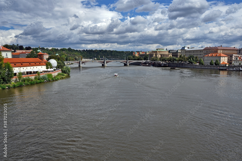 Fototapeta premium River in Prague with buildings in both sides. Clouds over the river. Vltava river