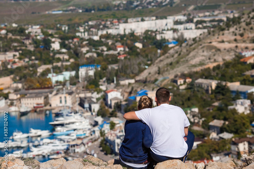 Мужчина и женщина-путешественники сидят на развалинах и любуются видом на город Балаклаву. Концепция отдыха и туризма.