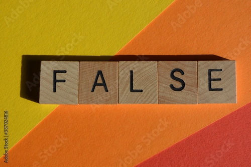 Slika na platnu False, word in wooden alphabet letters isolated on colorful background
