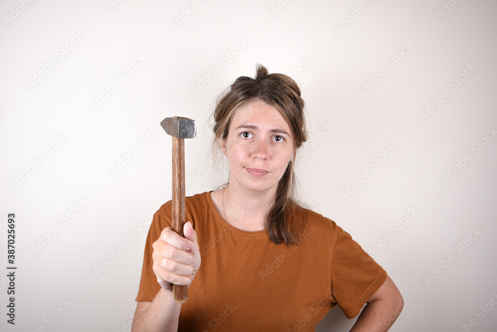 woman in brown T-shirt, holding hammer, looking at camera, isolated on white background. home renovation concept woman in brown T-shirt, holding hammer, looking at camera, isolated on white background. home renovation concept